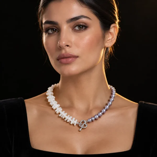 گردنبند مروارید نیم زنجیر نئو مینیمال Half Pearl Half Chain Collar با ترکیب مروارید شاخه ای سفید نامنظم و مروارید خاکستری نقره ای و قفل قلبی تاگل نقره ای روی گردن زن با لباس مخمل مشکی و پس زمینه مشکی لوکس