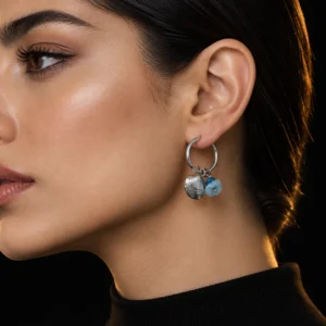 گوشواره حلقه ای استیل با آویز صدف دریایی و سنگ آبی اقیانوسی روی گوش مدل زن با لباس مشکی