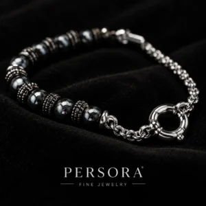 دستبند هایبرید حدید و زنجیر با قفل ملوان Gunmetal Hematite & Chain Sailor Bracelet با مهره های حدید گان متال مشکی تراش دار براق و اسپیسیر های نقره ای آنتیک طرح دار و زنجیر استیل رولو و قفل ملوانی حلقه ای نقره ای کلوزآپ روی پارچه مخمل مشکی با لوگوی PERSORA FINE JEWELRY و نورپردازی لوکس